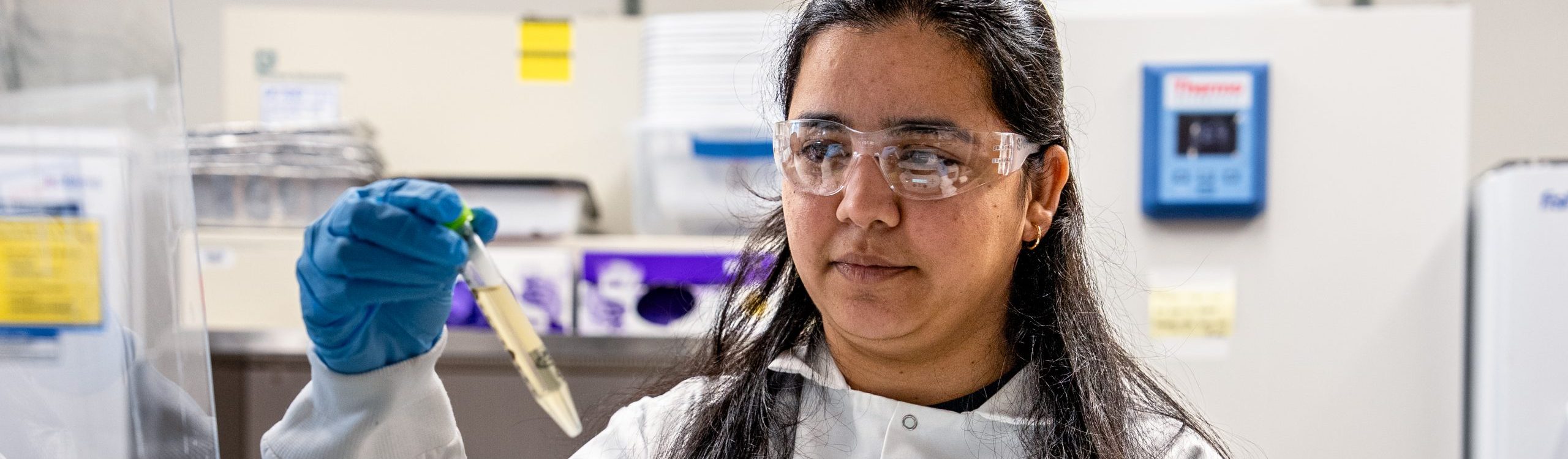 Researcher looking at a vial of liquid